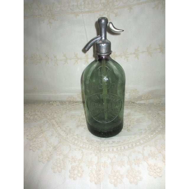 The vintage 1930's green Argentina handmade glass and metal 12" tall soda/seltzer bottle is a rare and unique collectible...