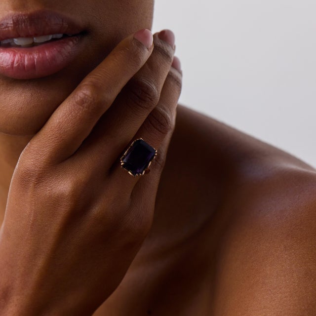 This beautiful amethyst cocktail ring is a striking vintage piece, centered by an emerald cut amethyst weighing...
