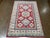 Hand-knotted Pakistani Kazak wool rug featuring a red field with bold geometric medallions and stylized floral motifs in...