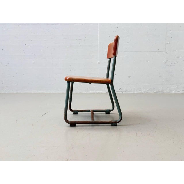 Small children's chair with a blue-green lacquered tubular steel frame in a sled shape and a solid wood seat and backrest...