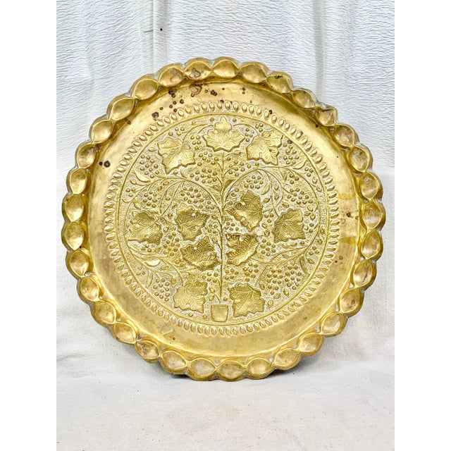 Large vintage brass tray. Made using the technique of repousse. Features a tree scene and scalloped edges. Has a hanger on...