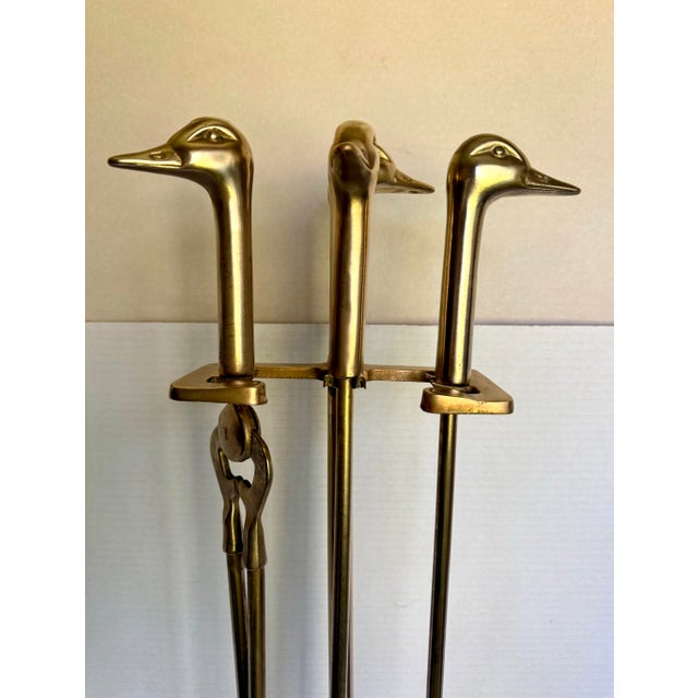 This vintage brass fireplace tool set features wonderfully sculptural duck head handles paired with a sleek geometric...