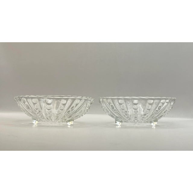 A pair of pressed glass bowls in a raised dot pattern fanning out from a central grouping of circles with three feet...