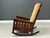 This rare form drop arm rocking chair features a sturdy, solid oak construction with a rich, dark finish that highlights...