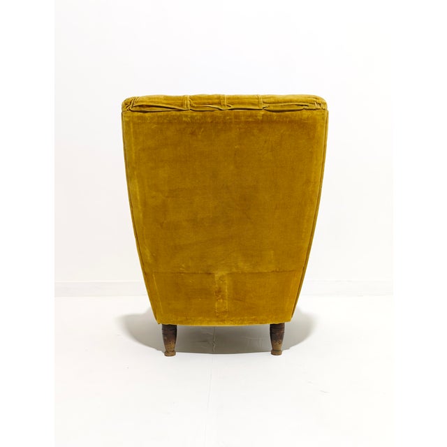 A single bedroom armchair with a pleasing shape. Upholstered in smooth mustard velvet with a tufted finish. Wooden legs.