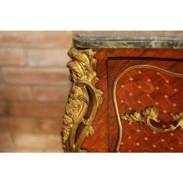 Vintage French Louis XVI style commode features shaped Italian green marble-top surmounting two-drawer chest in bombe form...