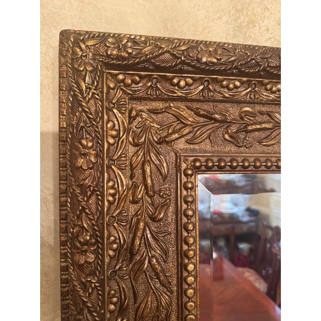 Rectangular wall mirror with a heavily embossed floral and beaded frame in a gilt/gold-tone finish, cast composition over...