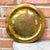 Small hammered brass round tray measuring 9.75” in diameter features a central geometric design that resembles a giraffe...