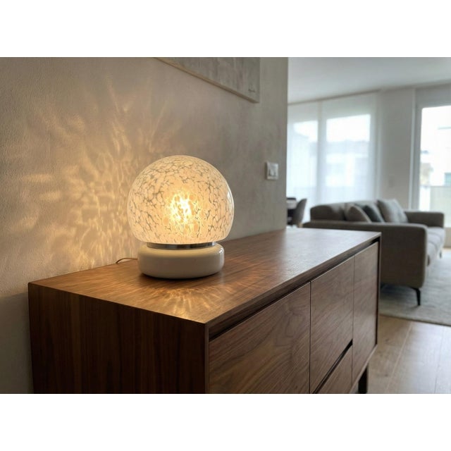 A 1970s murano glass lamp. Its enveloping spherical shape is crafted from the highest quality murano glass, featuring a...