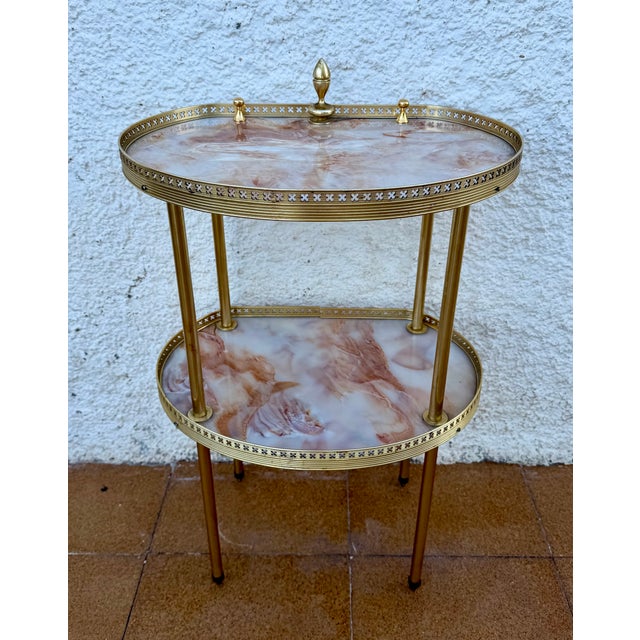 Elegant two-tier side table crafted in brass and onyx marble, featuring a refined oval silhouette and a light,...