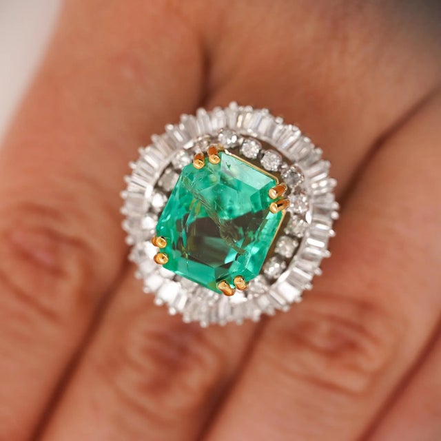This incredible ballerina-style ring features a vivid 9.17 carat emerald from the Chivor mine, framed by 3 carats of...
