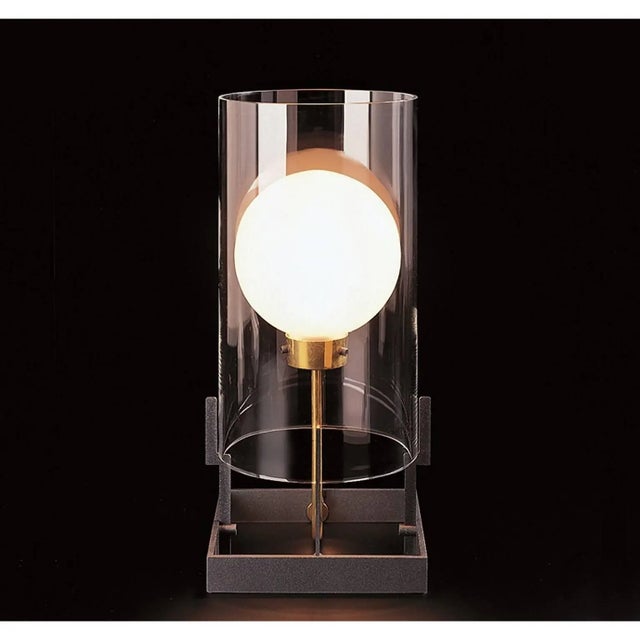 Table lamp of clear mouth blown Murano glass, anthracite painted iron and natural brass designed in 1984 by Carlo Moretti...