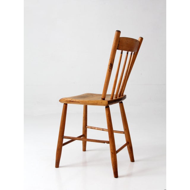 An antique plank seat chair featuring a hand-shaped saddle seat and a simple four-spindle back. Crafted in solid wood, the...