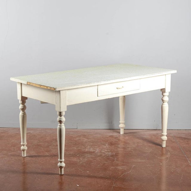 An authentic dining or work table with vintage charm, likely dating back to the mid-20th century, ideal for those seeking...