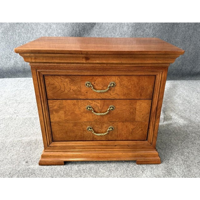 This Thomasville two-drawer nightstand features a beautifully figured burled walnut veneer, highlighted by rich tones and...