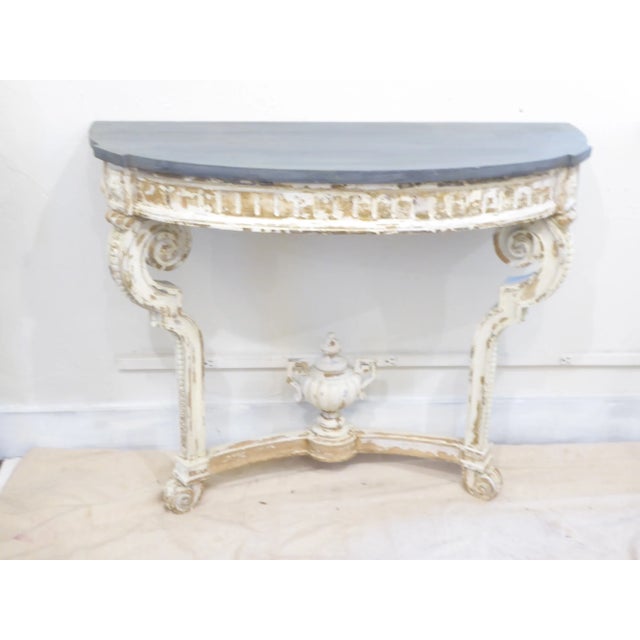 Antique carved wood demi-lune consoles with weathered finish, traces of gilding, faux slate painted tops, carved baskets...