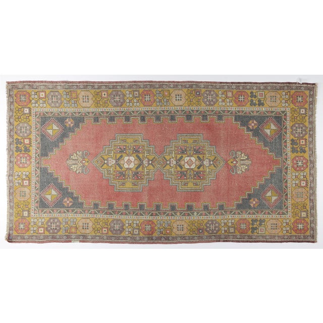 This vintage handwoven Turkish rug features a striking stepped-medallion design set against a softly faded red field. Rich...