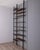 Two-section floor-to-ceiling bookcase, with black metal frame and wooden shelves, gold-plated brass feet and ceiling tips,...