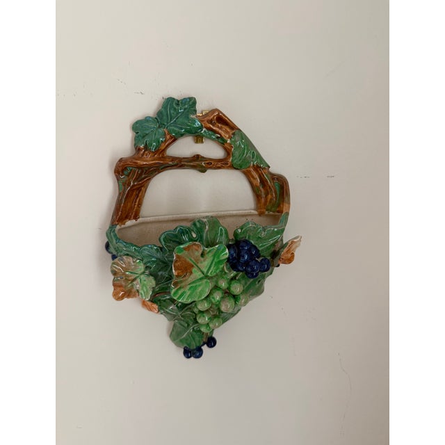 A charming vintage majolica-style wall pocket, hand-molded and glazed to resemble a woven basket overflowing with grape...