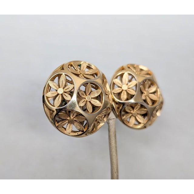 1960s round goldtone with cut out flowers clip earrings. Marked crown "TRIFARI ©" on the clips. Measure: 1 3/8 inches...