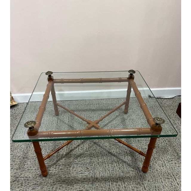 Fabulous faux bamboo wood with glass top and antiqued brass finials coffee table . Circa 1970’s Measures 36” x 48” x 17” h...