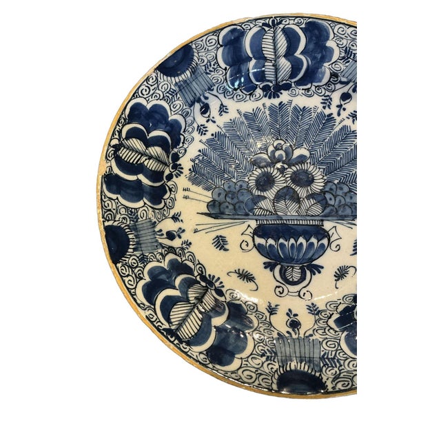 This is a classic piece of 18th century Delft. The central motif shows a decorative urn overflowing with flowers and large...