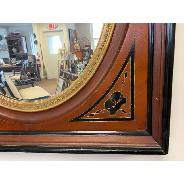 19th Century Eastlake Victorian wall mirror. Heavy wood frame with gold and black detailing. Gold oval inset with wood...