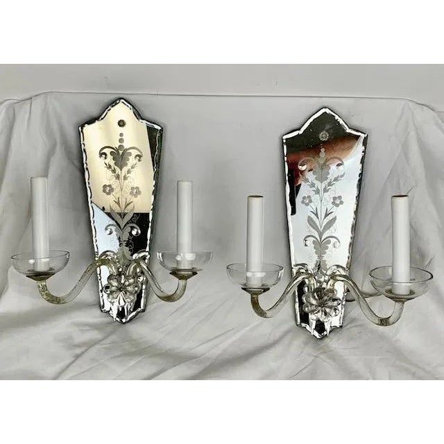 A beautiful pair of 1920a mirrored wall sconces, featuring elegantly etched and carved glass backplates that reflect light...