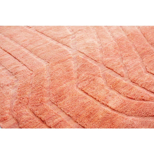 Vibrant hand-knotted wool rug in warm Burnt Sienna and Shell Coral hue with subtle, flowing line patterns. The...