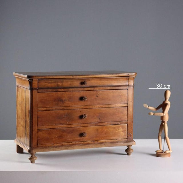 Model of a Cappuccino chest of drawers in walnut. Four drawers, the first of which is under the top. It features two...