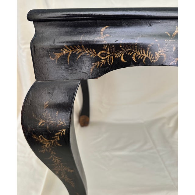 A late 19th century black japanned Chinoiserie side table, adorned in delicate gilded floral motifs, with apron fronts,...