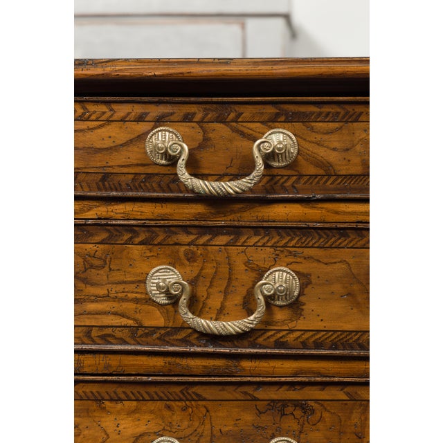 An English George III period burl wood chest-of-drawers from the early 19th century, with feather banding inlay and bronze...