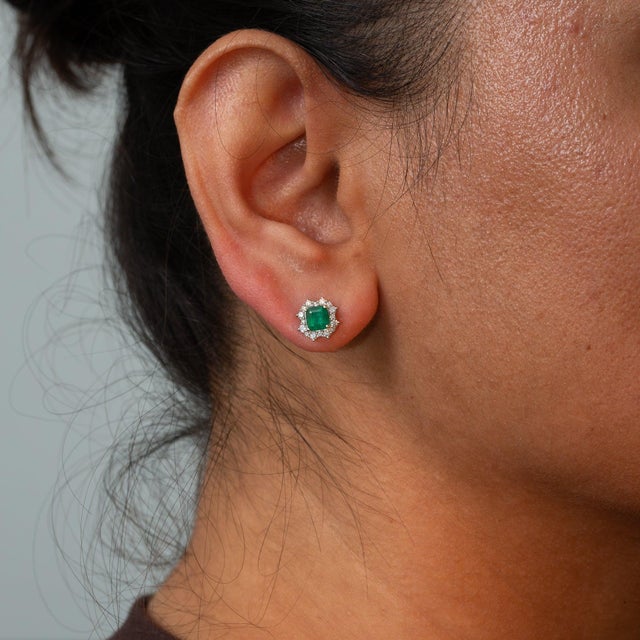 Set in solid 14K white gold, these earrings pair two emerald-cut colombian emerald stones of 0.42 carats with thirty-two...