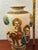 Antique Asian ceramic vase featuring sculptural figural scenes accented by an elephant motif. Finished in a warm ivory...