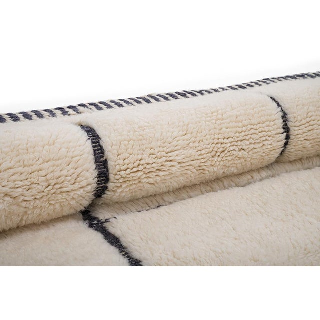 Minimalist hand-knotted wool rug with a modern geometric design in Ivory and Jet Black. The hand-woven linear pattern...