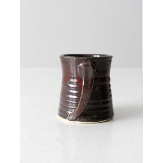 This is a vintage studio pottery mug. The handmade mug features a dark brown glaze with reddish undertones. Lovely shape...