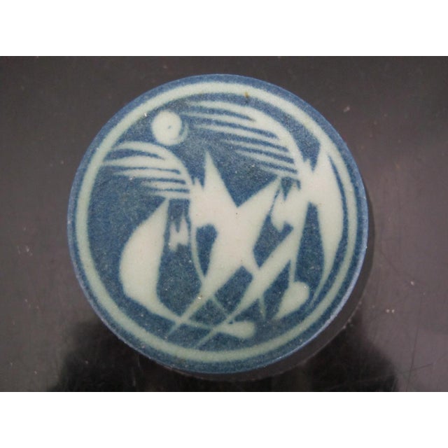 Small circular pottery box with lid. In blue and white showing an abstract, possibly stylized bird design on the lid and...
