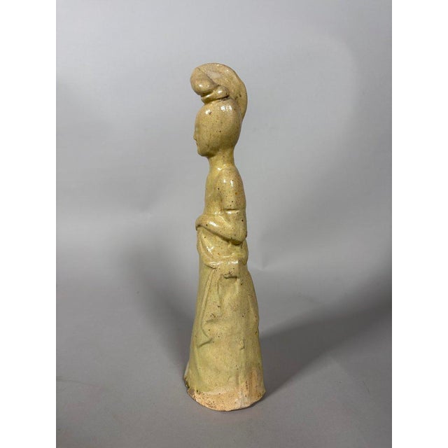 Sculpture of a Sui Dynasty Court Lady (581-618). This terracotta sculpture, painted with a yellow glaze, depicts a lady of...