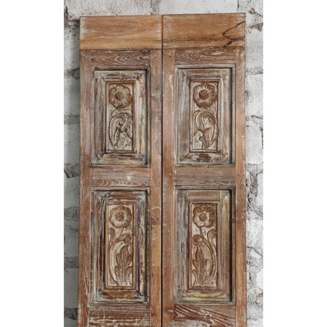 An authentic antique carved wood door featuring a classic six-panel design with rich texture and timeworn patina....