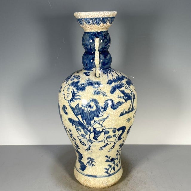 A striking Chinese blue and white porcelain vase featuring a heavy, all-over crackle glaze. The vase has a baluster shape...