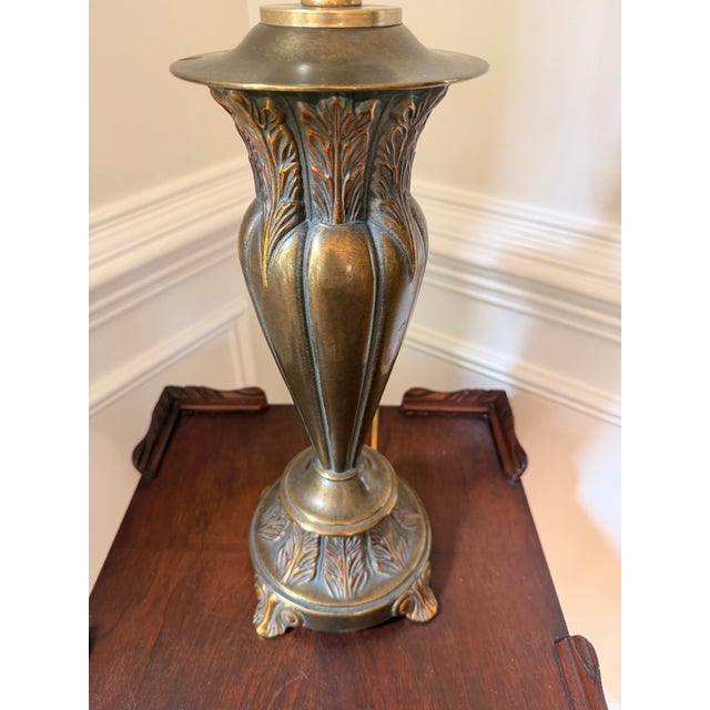 Elegant heavy vintage table lamp with a sculptural urn-form body, raised acanthus leaf detailing, and an antiqued brass...