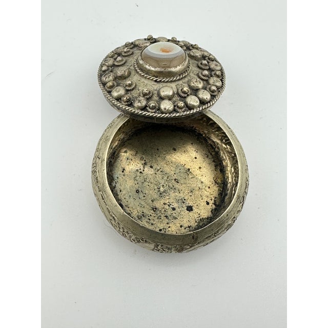 Vintage round silver toned box featuring intricate embossed or chased floral designs. This is a pre owned item so please...