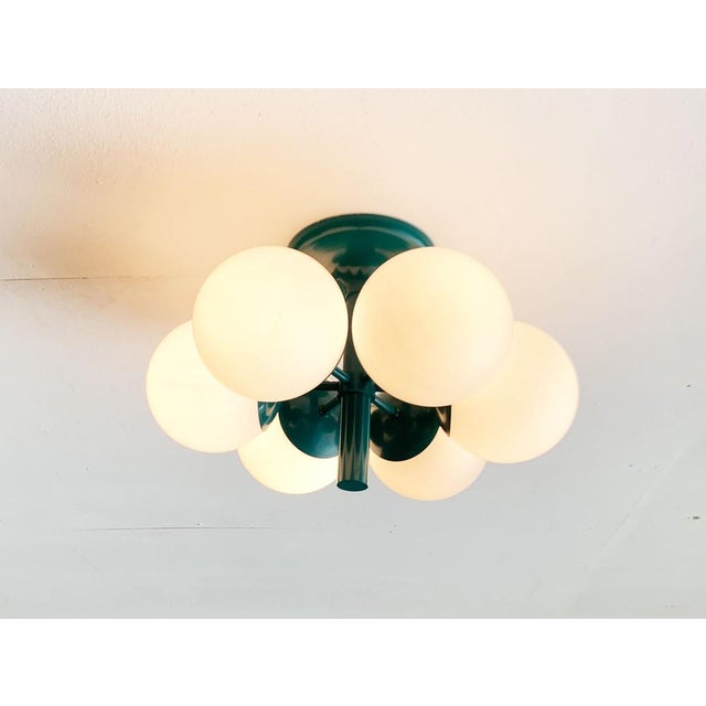 Imposing Space Age ceiling or wall lights from Kaiser glow in a special color. The central luminaire body is kept in...