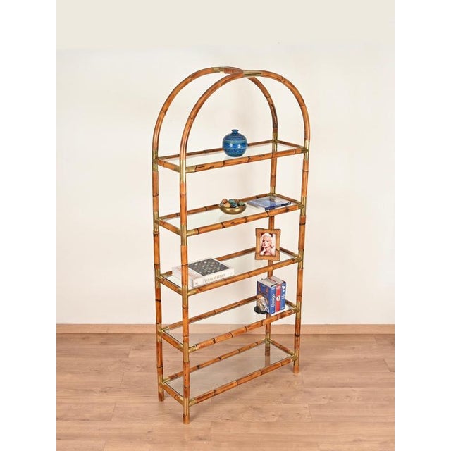 Stunning and one-of-a-kind large arched bookcase in rattan and brass with crystal shelves. This exceptionally elegant...