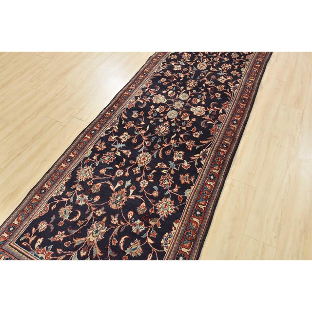This authentic vintage traditional Sarouk runner is hand-knotted with fine wool and natural dyes. This rug features an...