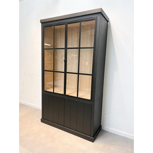 This elegant black display cabinet combines modern design with practical storage. Featuring large glass-paneled doors with...