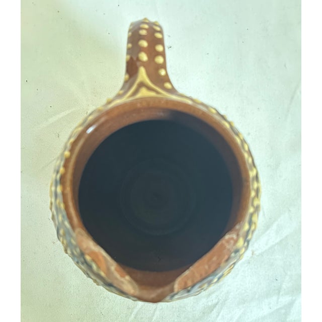 This wise owl slipware pitcher from England has geometric shapes consisting of lines, dots, circles, and triangles.