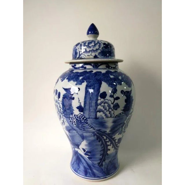 This blue and white porcelain vase is adorned with hand painted mythical birds and flowers. Antiquing process applied...