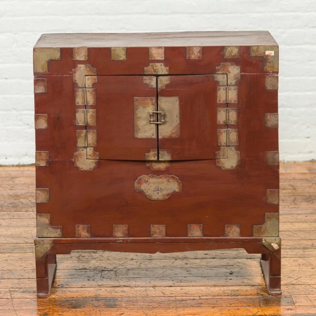 An antique Korean side chest from the early 20th century, with petite double doors and traditional brass hardware. Created...