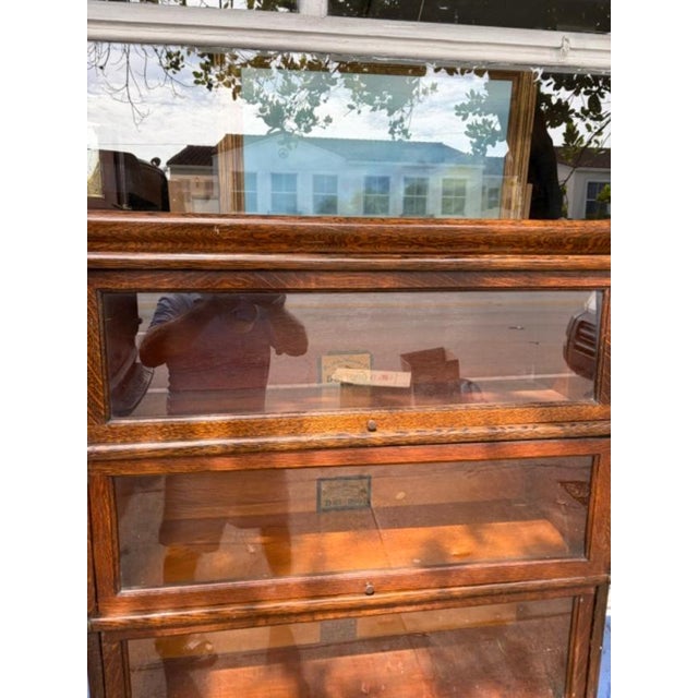 The Globe Wernicke Co Cincinnati Bookcase is an antique piece of furniture made of oak with a brown finish. It features a...